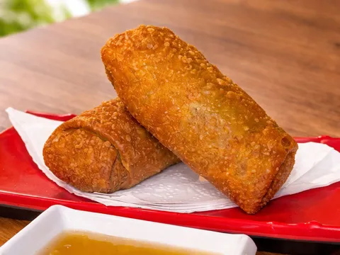 Two golden fried beef and pork lumpia from Wok Dong served on a red tray with dipping sauce