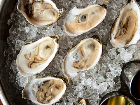 A metal tray of freshly shucked oysters on crushed ice with mignonette spoons at Hen of the Wood in Burlington