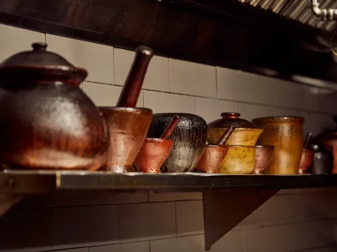 Collection of well-worn clay mortars and cooking pots on a tiled kitchen shelf at Pusadee's Garden Thai restaurant in Pittsburgh