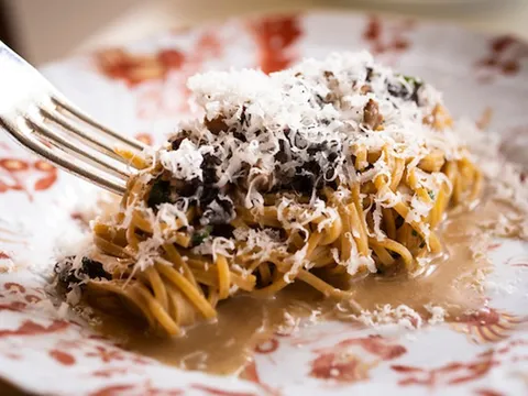 Plate of hand-cut pasta topped with shaved cheese in a light sauce on a patterned plate at Vetri Cucina in Philadelphia
