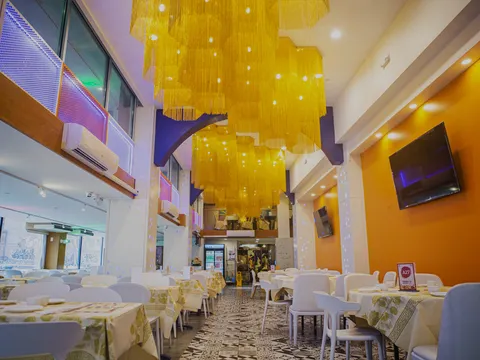 Bright two-story dining room at Hei La Moon in Boston Chinatown with gold chandeliers and set tables