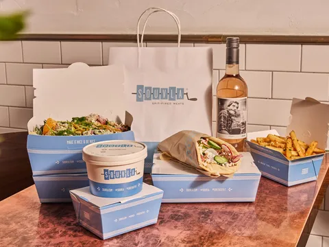 A Souvla takeout spread of a Greek salad, gyro-style pita sandwich, Greek fries, avgolemono soup, and rosé at Souvla in San Francisco.