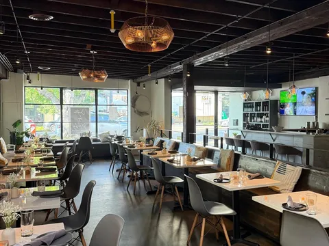 Dining room at Meesha, with tables on a concrete floor, a bar at the back and windows onto the street