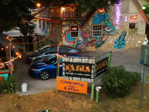 Mural-covered exterior and lit patio of Nasha on East 7th Street in Austin at dusk
