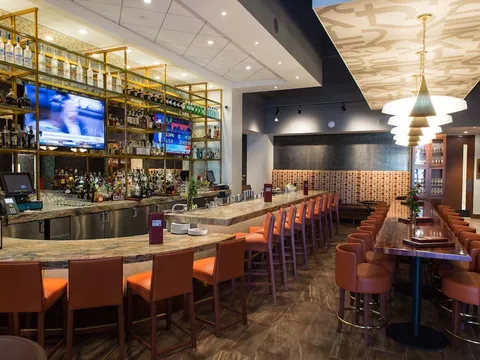 Bar and dining room at Kiran's, with a long bar, high stools and pendant lighting