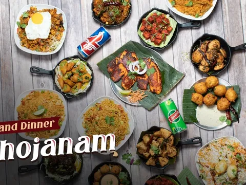 Overhead spread of Godavari's Grand Dinner Bhojanam — biryanis, dosas, tandoori fish, curries and fried appetizers in cast-iron skillets, promotional photo from Godavari in Woburn, Massachusetts