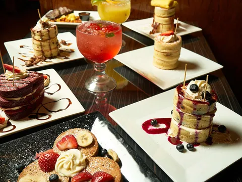 Brunch plates and a cocktail arranged on a dark table at Superhero Chefs
