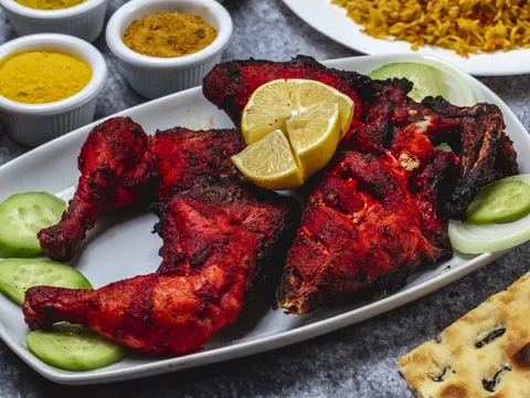 A platter of tandoori chicken at Incredible India in Indianapolis, garnished with lemon and cucumber, served with dishes of spice powders, biryani and naan