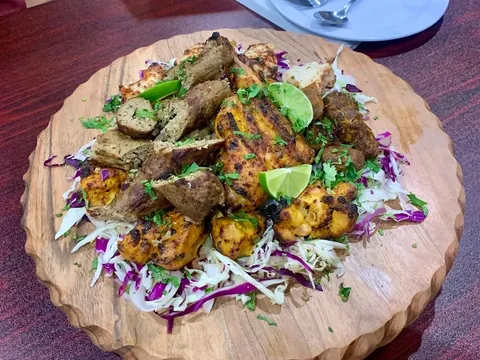 A platter of grilled kebabs, chicken, and vegetables from Tikka N Kabab.