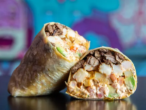 Lucha Libre Taco Shop's Surfin' California Burrito cut in half showing steak, shrimp, fries and avocado