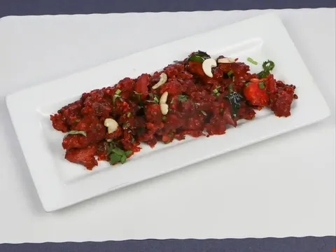 A plate of Andhra-style dry red chilli chicken fry garnished with roasted cashews, curry leaves and cilantro at Desi Ruchulu Indian Cuisine in Ann Arbor, Michigan