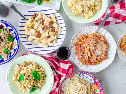 Overhead spread of house-made pasta dishes in DiAnoia's Eatery hand-painted ceramic bowls with focaccia and wine in Pittsburgh