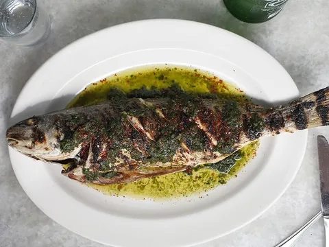 Whole grilled fish served with herb sauce at Pêche Seafood Grill