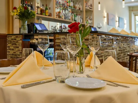 Set table with folded napkins and wine glasses in front of the bar at Cloves Indian Cuisine