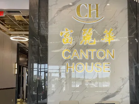 Marble reception wall with illuminated gold Canton House (富麗華) signage and gilded guardian lion statues inside the Chamblee restaurant