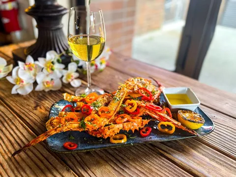 Grilled seafood platter with sliced chiles and a glass of white wine on a wood table at Tequila 61 in Anchorage, Alaska