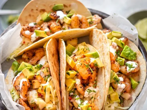 Tray of classic yellow-cheddar hard-shell beef tacos with fresh salsa and chips at Tito's Tacos