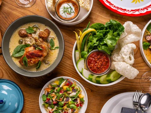 Overhead spread of Thai dishes at Kin Khao including green curry, namprik relish with vegetables, and charred squid