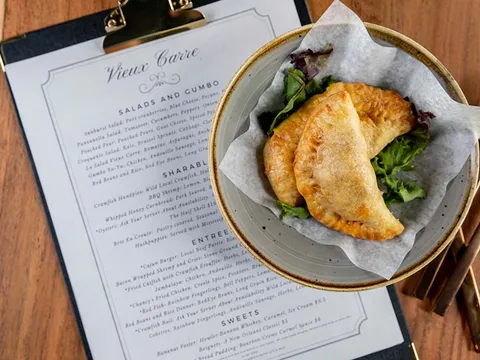 Fried crawfish handpies on a plate next to the Vieux Carré menu