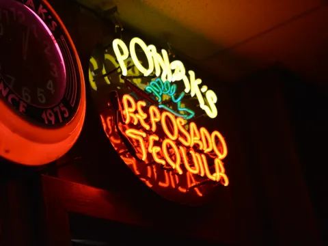 Interior of Ponak's Mexican Kitchen & Bar in Kansas City, showing a glowing neon 'Ponak's Reposado Tequila' sign beside a red 'Since 1975' wall clock