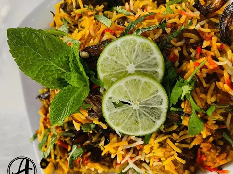 Plate of biryani garnished with mint and lime slices at Aroma Indian Cuisine