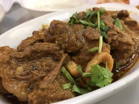 Goat karahi garnished with cilantro in a white dish at Shan Restaurant.