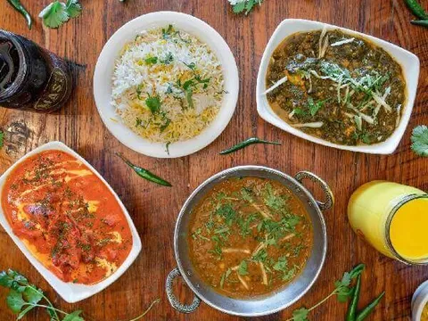 Overhead spread of rice, curries, naan, and mango lassi at Masti Indian Street Eats
