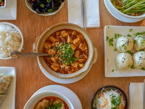 Overhead spread of Pine & Crane Taiwanese dishes including mapo tofu, panfried pork buns, dan dan noodles, beef roll and rice