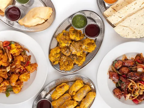An overhead spread of appetizers at New Taste of India in Portland: samosas, pakoras, papadums, gobi manchurian and chili chicken