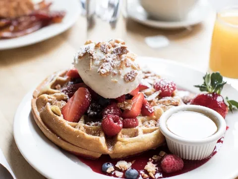 Clinton St. Baking Company buttermilk waffle topped with fresh berries, whipped cream and toasted nuts with maple butter and coffee