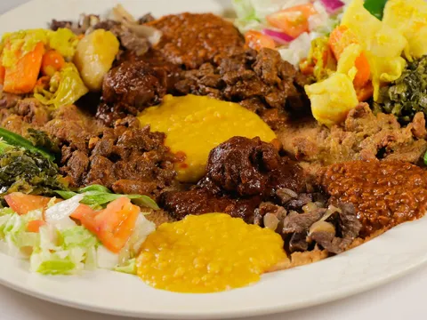 An Ethiopian combination platter at Messob with beef and vegetable stews, collard greens, salad and jalapeños served over injera