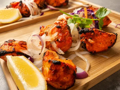 Tandoori chicken pieces with onions, cilantro, and lemon at Cumin Lakeview