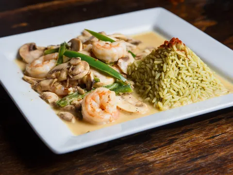 Tequila Museo Mayahuel's Camarones Moctezuma al Tequila — sautéed shrimp with mushrooms and green beans in a light tequila cream sauce alongside a mound of green rice on a white plate