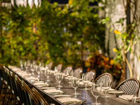 Pasjoli garden dining table set beneath glass pendant lights and greenery